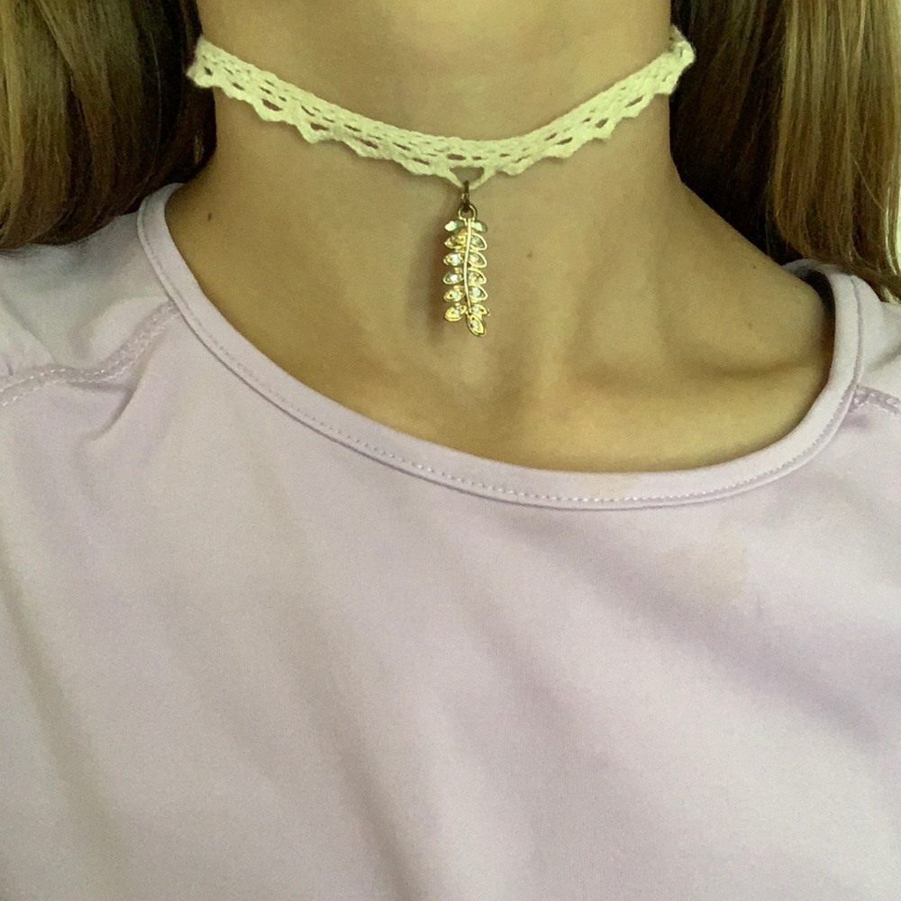 white choker with a gold leaf-like charm
